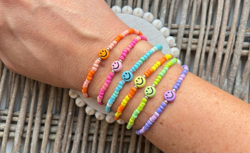 A Person'S Wrist Adorned With A Collection Of Colourful Beaded Bracelets Featuring Silver Heart Charms